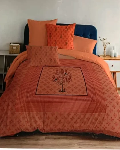 Rust orange bedding set with tree of life bird print and matching cushion covers on navy blue bed
