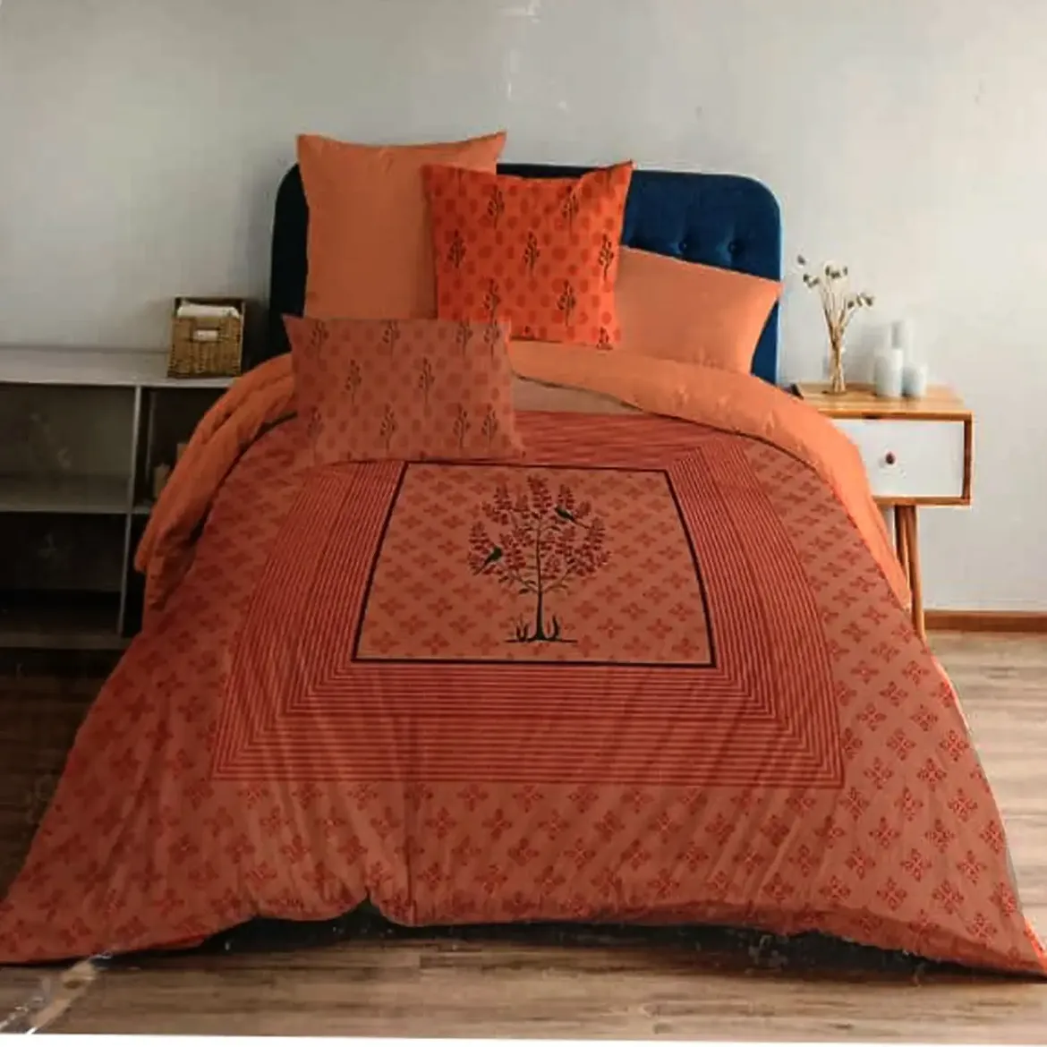 Rust orange bedding set with tree of life bird print and matching cushion covers on navy blue bed