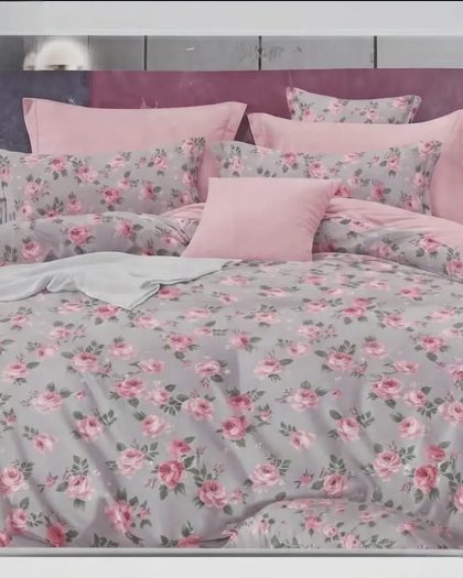 Elegant pink floral bedsheet set with rose prints, matching pillows, and soft pink bedding in a modern bedroom.