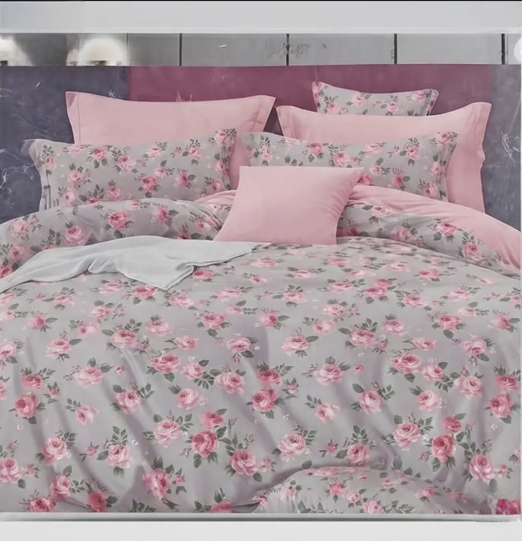 Elegant pink floral bedsheet set with rose prints, matching pillows, and soft pink bedding in a modern bedroom.