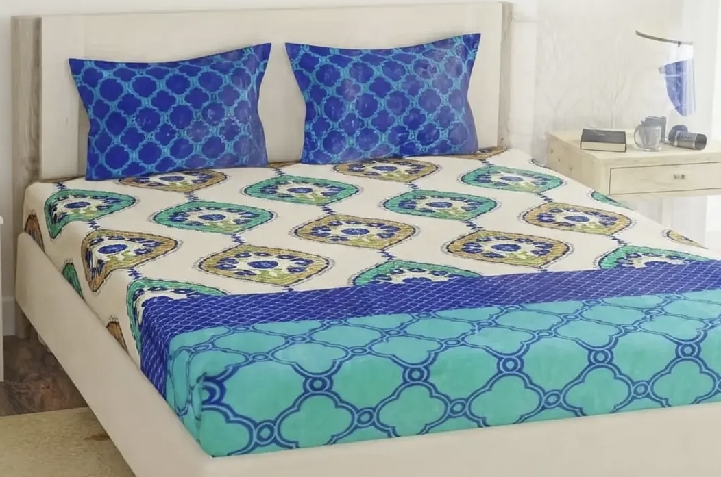 Blue and green geometric printed bedsheet set with decorative patterns and matching blue pillow covers.