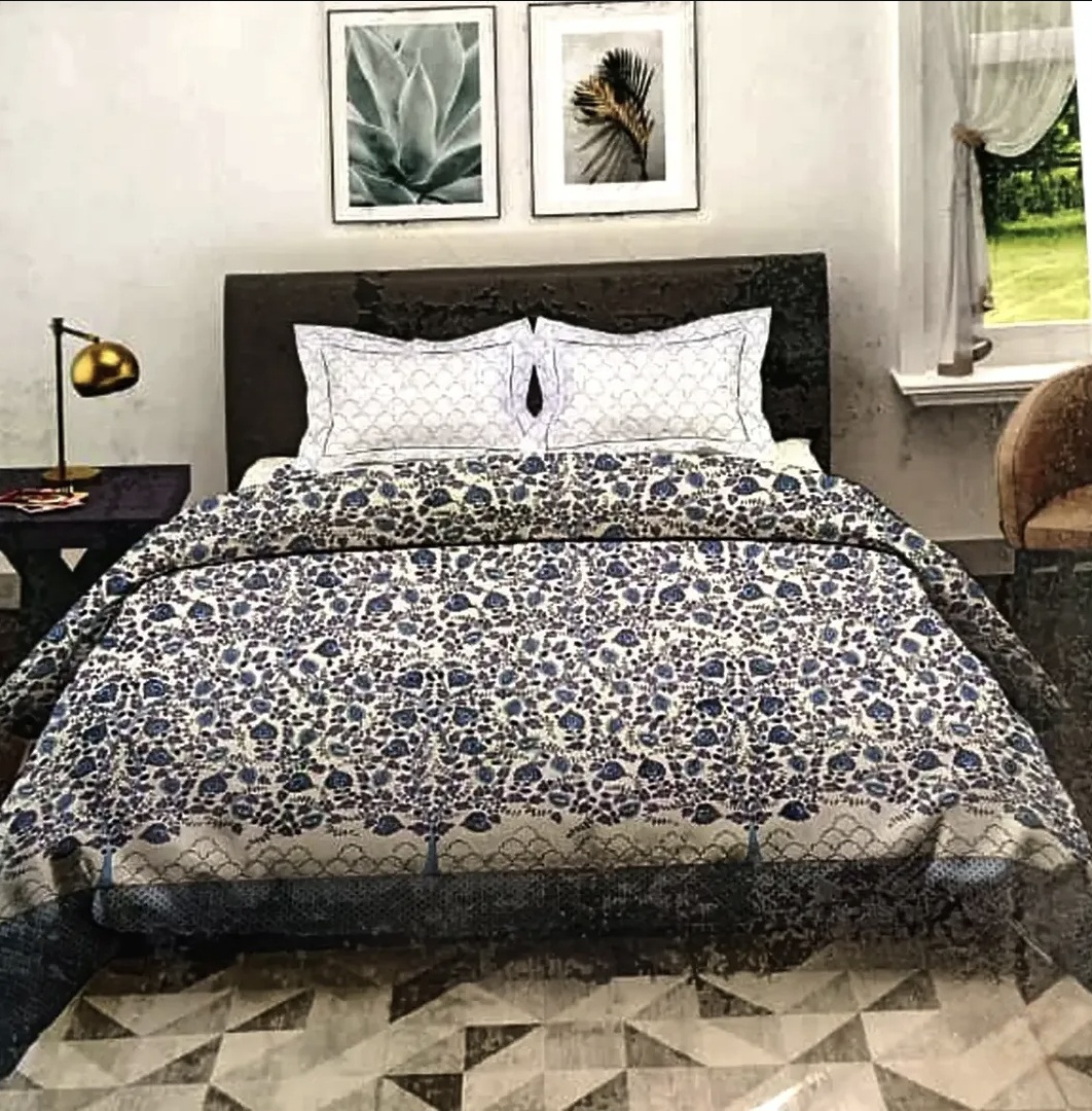 Blue and beige floral printed cotton bedding set with scalloped pillow shams on wooden bed frame
