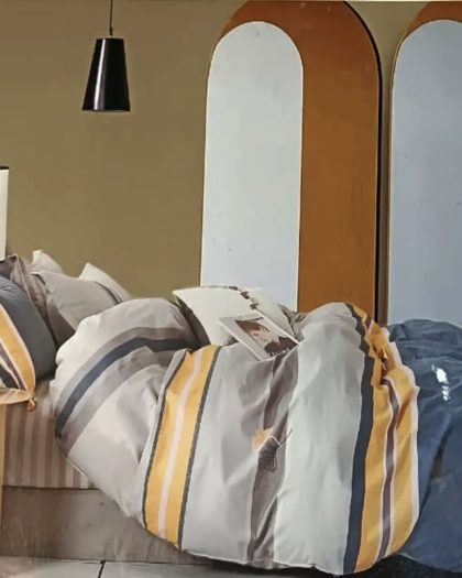 Gray, mustard yellow, and navy striped cotton bedding set styled on a bed with modern arch-panel headboard