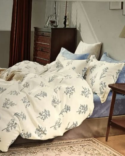 Ivory and blue floral sprig printed cotton bedding set with matching pillow shams on vintage bed