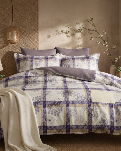 Elegant bedroom featuring a purple and cream floral checkered bedsheet set, matching pillows, and a soft white throw blanket.