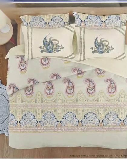 Cream paisley printed cotton flat bedsheet with four embroidered pillow covers on wooden bed